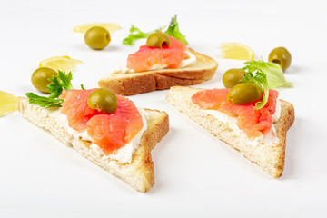 Fototapeta na wymiar Appetizer, open sandwich with salmon and soft cheese on white background. Traditional Italian or Scandinavian cuisine. Concept of proper nutrition and healthy eating. Flat lay, copy space for text