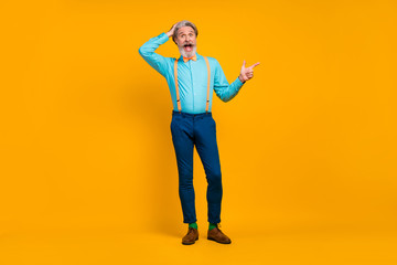 Fototapeta na wymiar Full length photo of cool trendy grandpa charismatic person stylish look direct finger empty space wear shirt suspenders bow tie pants boots socks isolated yellow color background