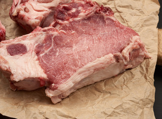 raw juicy pork slices of meat on the rib, food lies on brown parchment paper