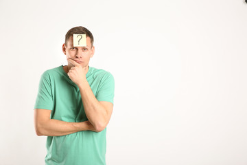 Fototapeta premium Thoughtful man with question mark on white background