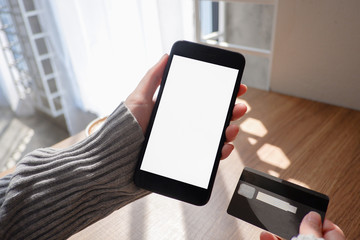 Mockup picture of business woman’s hands holding smart phone with white blank screen in modern place