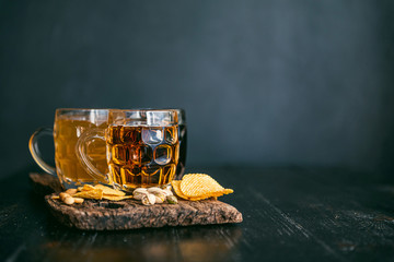three glasses of expensive craft beer, classic and unfiltered and dark in a glass on the table with a snack of peanut and pistachio chips and nachos