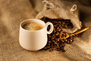 Coffee cup with cinnamon sticks and coffee bag on wooden table