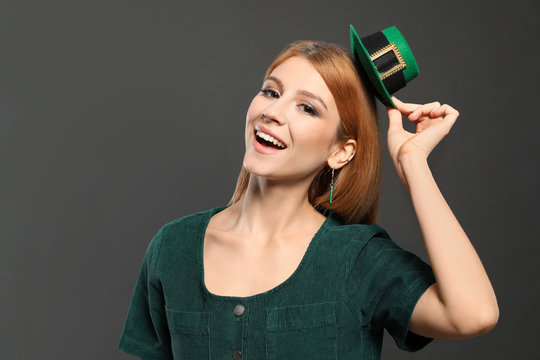 Young woman with green leprechaun hat on grey background. St. Patrick's Day celebration