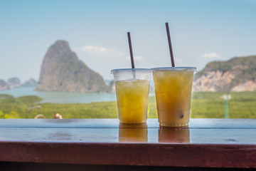 Glass of juice on the wooden table with Aerial view Phang Nga Bay, Beautiful View of Phang Nga Bay from Samet Nang She Viewpoint, Thailand.