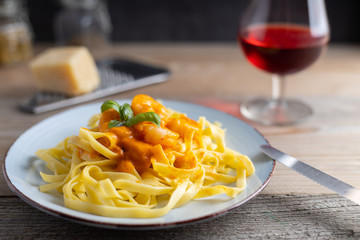 homemade tagliatelle with diabolo sauce with shrimps on a plate.