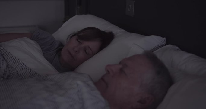 Senior adult couple sleeping in bedroom at night, day in life