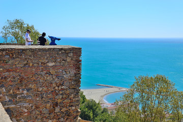 Malaga, Spain - March 4, 2020: Tourists from the Gibralfaro Castle contemplate the coast and Port...