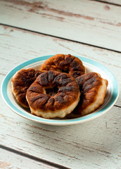 Tasty homemade fried dough with minced meat or belyashi. Pies are on a white and blue plate on a wooden table. Side view. Copy space. Vertical orientation