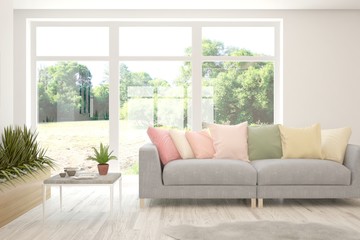 Minimalist living room in white color with sofa and summer landscape in window. Scandinavian interior design. 3D illustration