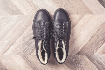 Top view of winter warm fashion male shoes on wooden background. Sale and shopping concept. Copy space.