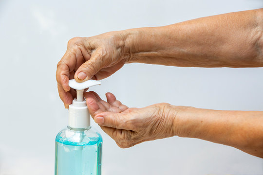 Senior woman's hand is pressing bottle of sanitizer gel pump dispenser to wash her hands in grey background. Close up & Macro shot, Select focus, Prevention from covid19, Bacteria, healthcare concept