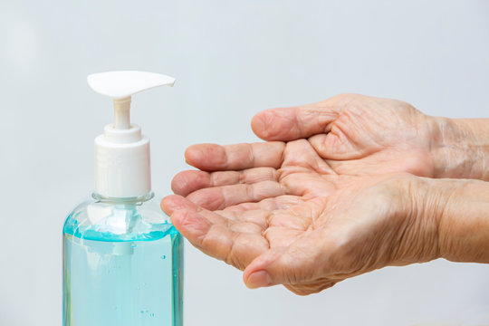 Senior woman's hand is using bottle of sanitizer gel pump dispenser to wash her hands in grey background. Close up & Macro shot, Select focus, Prevention from covid19, Bacteria, healthcare concept