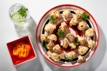 Spicy roasted cauliflower florets with mango pepper dipping sauce seen from above