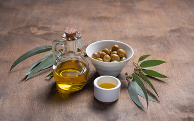 ripe natural eco friendly olives with olive oil in a bottle on a brown wooden background.