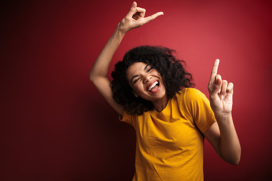 Image of african american woman with curly hair smiling and dancing