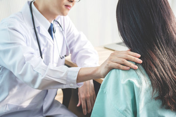 Obraz premium Friendly male doctor consoling female patient and use your hand to shoulder to help her relax in office during reception, The concept of counseling and health care.