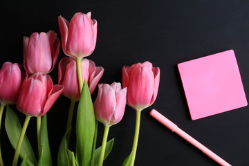 Tulips and notebook for writing on a black background