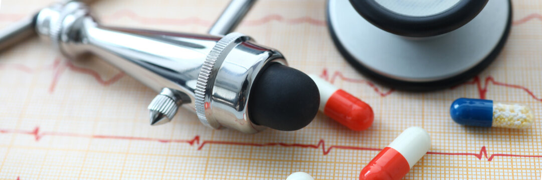 Medical instruments and pills lying at electrocardiogram paper