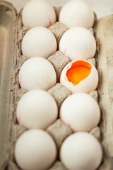 Broken white egg in a cardboard box top view