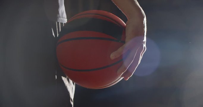 Close-up of a basketball player holding a ball bright light shadow silhouette flare ray