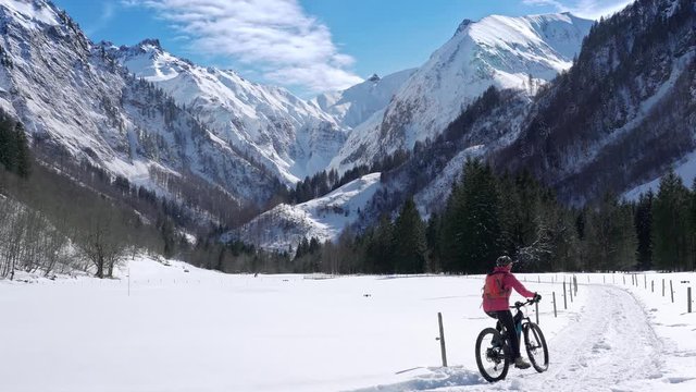 nice senior woman riding her e mountain bike in winter in the awesome scenery of the Allg&auml;u Alps near Oberstdorf, Bavaria, Germany