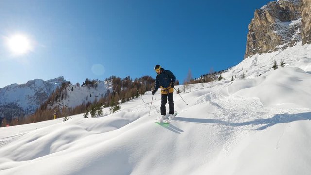 FOLLOW CLOSE UP: Happy skier having fun skiing backcountry on a sunny winter day in snowy mountains. Extreme freeride skier riding fresh powder snow off piste in mountain ski resort in dolomites Italy