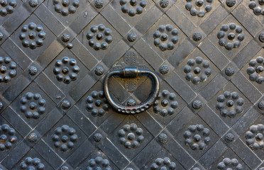 Elements of architectural decoration of ancient buildings, an old metal forged door and lattice gates, a doorknob and a knocker. On the streets in Lviv, public places.