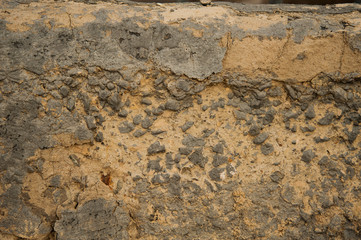 texture of a sand wall with grey stones,the yellow-grey background is cracked and destroyed,the background of yellow sand color with gray details