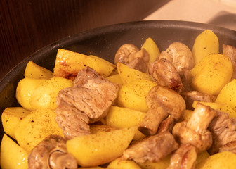 Fried potatoes with meat, spices and mushrooms
