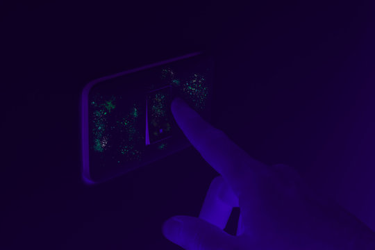 Ultraviolet UV Blacklight Exposing Germs And Virus On Hand Touching Dirty Light Switch