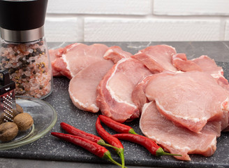Raw pork steaks on a marble board with spices