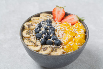 Healthy smoothie bowl with mango, strawberry, blueberry, banana, Chia seeds and granola. Healthy vegan diet food concept.