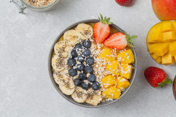 Healthy smoothie bowl with mango, strawberry, blueberry, banana, Chia seeds and granola. Healthy vegan diet food concept. Top view