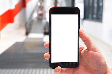 Hand holding mobile phone on escalator background. Focus on the hand. Concept of using mobile apps