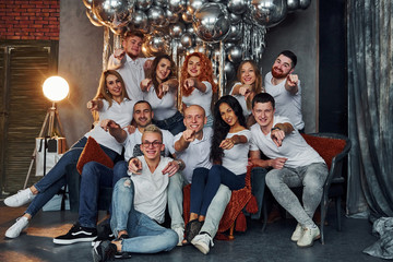 Happy young people celebrating New Year in christmas decorated room with lighting equipment