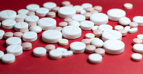 Heap of white pills, tablets, capsules on red background. Drug prescription for treatment medication health care concept wth copy space.