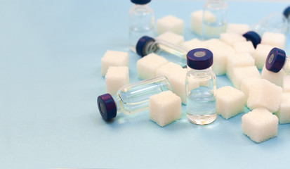 Sugar addiction, insulin resistance, unhealthy diet, sugar cubes and bottles of insulin on blue background, diabetes protection medical concept.