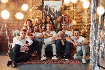 Smiling young people celebrating New Year in cozy christmas decorated room together