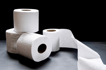 Rolls of white toilet paper lie on a black background