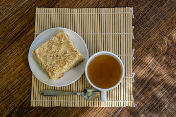 Cup of tea with cake on brown table background