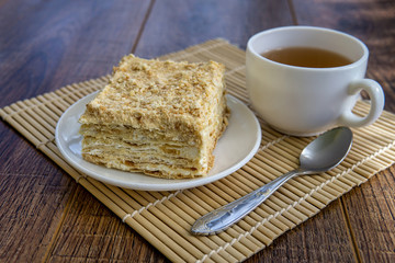 Cup of tea with cake on brown table background