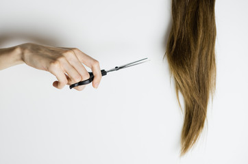 Close up - Unrecognizable upset woman cuts her long straight hair with scissors. Copy space.