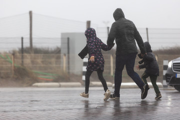 family crossing a street while it is heavy raining