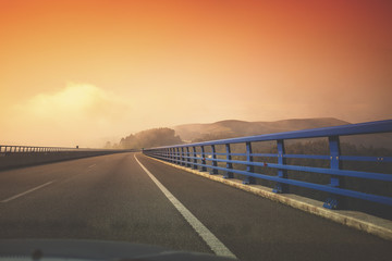 View of the bridge over the river through the windscreen. Beautiful evening landscape with the highway at sunset. Asturias, Spain