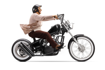 Fototapeta na wymiar Elderly female biker with a helmet riding a custom chopper motorbike