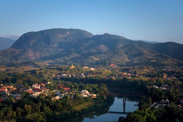 Fototapeta na wymiar Elevated view of the city of Luang Prabang, Laos, traversed by the Nam Kham river and surrounded by thick rainforest, in the afternoon.