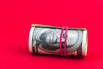 roll of 100 dollar banknotes on red background