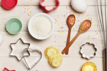 Baking utensils and ingredients. Colorful silicone cooking utensils, rolling pin, cookie mold,. cupcake cases and sugar sprinkling on a white wooden background. Easter concept.