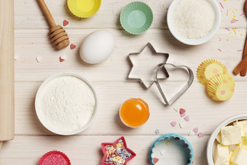 Baking utensils and ingredients. Colorful silicone cooking utensils, rolling pin, cookie mold,. cupcake cases and sugar sprinkling on a white wooden background. Easter concept.